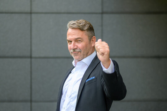 Triumphant stylish businessman giving a thumbs up gesture