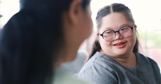 Back view of unrecognizable woman hugging cute girl with down syndrome and expressing love whie sitting on couch at home