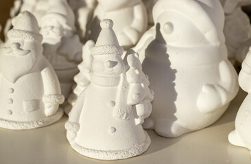 many gypsum figurine for painting lessons school activities for kids.white christmas shapes fir tree,santa claus, gnome snowman placed of shelf for sale in shore art store winter diy do it yourself - obrazy, fototapety, plakaty