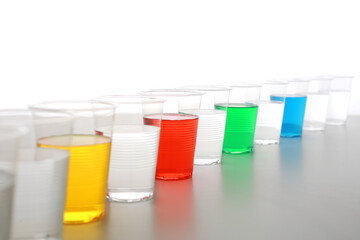 色の付いた水が入った瓶やコップ