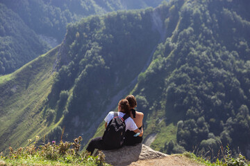 Romantic couple of women in love sitting on the mountainside admire the view of the mountains. Same-sex relationships normal life