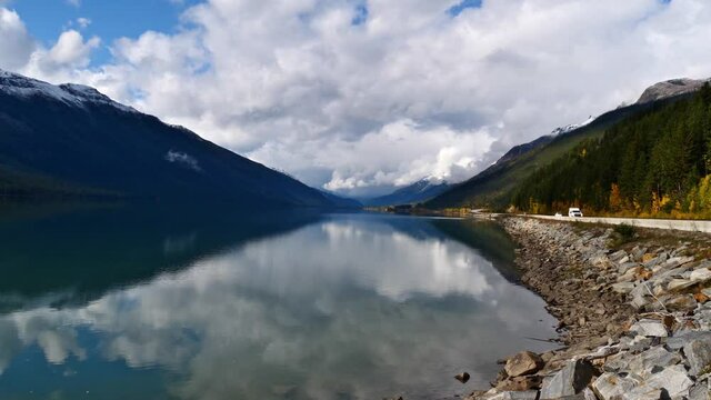 Beautiful view of Moose Lake in Mount Robson Provincial Park in British Columbia, Canada in the Rocky Mountains on cloudy day in autumn season with water reflections and cars on Yellowhead Highway pas