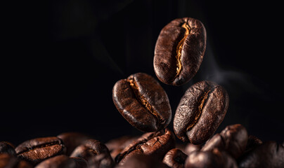 Obraz premium Coffee beans with smoke on black background , Freshly Roasted coffee beans