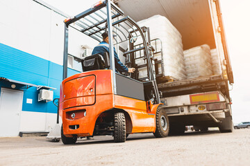 A man on a forklift works in a large warehouse, unloads bags of raw materials