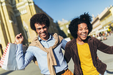 Obraz premium Beautiful young loving couple carrying shopping bags and enjoying together.