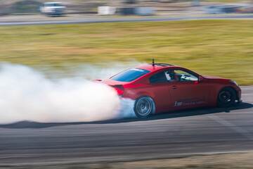 Red Drift Car / Race car drifting around corner very fast with lots of smoke from burning tires on...