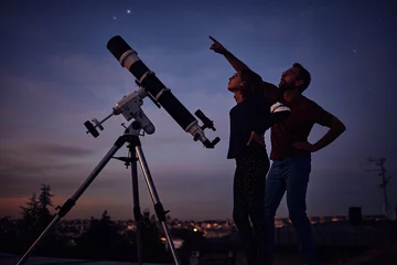 Fotobehang Silhouettes of father, daughter and astronomical telescope under starry skies. © astrosystem