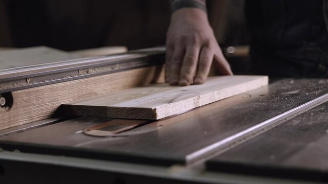 carpenter work with machine circular saw. electric saw machine blade and board in a wood shop. workers sawing boards with a circular saw