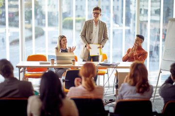 A group of participants is congratulating to a young businessman on an interesting business lecture in the conference room. Business, people, company