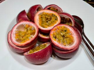 Close up of fresh passionfruit (maracuja) halves on white plate.