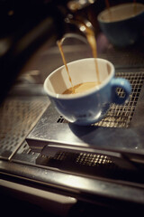 Close-up of an espresso pouring into a cup in the apparatus. Coffee, beverage, bar