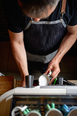 A bird-eye view on barman's hands using a milk to make an espresso. Coffee, beverage, bar
