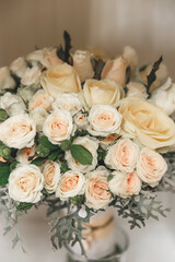 bridal bouquet of cream roses on white surface on blurred background