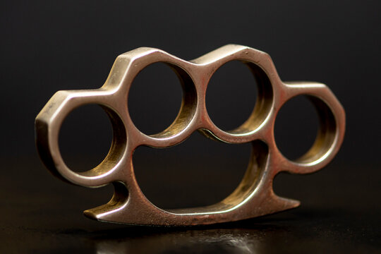 Steel brass knuckles on a black background with reflections. Concept: hooligan fight, fighting without rules, street banditry, injuries.