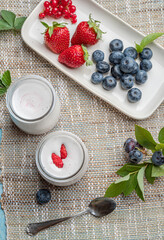 Two glass containers with plain yoghurt and berries on the table. Light summer mood.