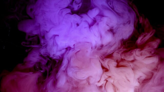 Pink paint creates abstract clouds. Artistic backgrounds. The fuchsia liquid swirls in beautiful clouds.
