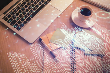 City drawing over computer on the desktop background. Top view. Double exposure. Smart home concept.