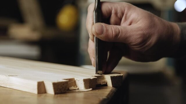 close up. a woodworker cuts out a dovetail on a pine board with a chisel. dovetail joinery is done with a hand tool. woodworker makes dovetail