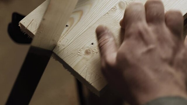 a carpenter cuts out a dovetail on a pine board with a hand saw. dovetail joinery is done with a hand tool. craftsman makes an antique spike to connect parts