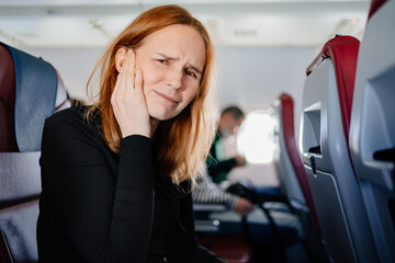 a woman on an airplane has a headache and an earache while flying on an airplane