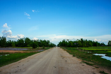 Fototapeta na wymiar 都心から離れたカンボジアの田舎道と青空