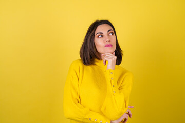 A young woman in a cozy yellow sweater on a background with a bright pink lip gloss looks to the side with inspiration, dreamily, pensively