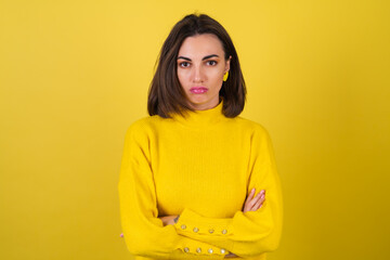 Young woman in a yellow cozy sweater on the background with bright pink lip gloss is upset,...