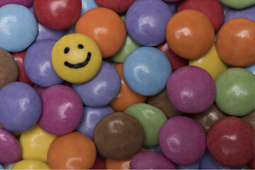 one yellow smiley between colorful round sweets