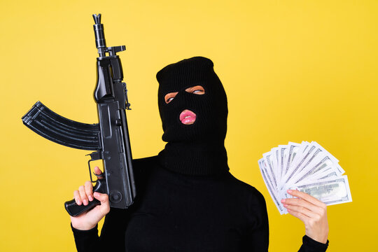 Young Sexy Beautiful Woman With Bright Pink Lips, Balaclava On Her Head, Holding A Fan Of 100 Dollars And Weapon Machine Gun, Hacker, Robbery, Fraudster