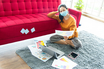 Work from home concept. Young Asian beautiful woman using laptop with gadget while sitting on gray carpet at home.