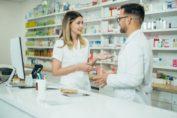 Happy young male and female colleagues pharmacist working in a pharmacy