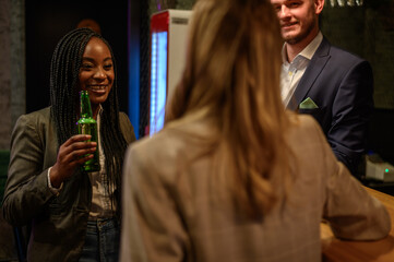 Woman drinking beer in the bar with her colleagues after work