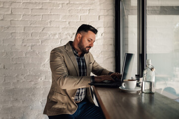 Businessman working on his laptop while drinking coffee in a cafe