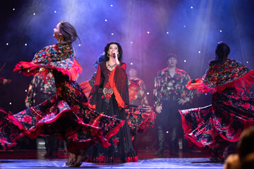 A team of musicians, singers and dancers in gypsy costumes singing and dancing on stage