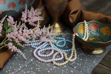 Oriental fairy tale still life of beads, flowers and antique metal copper vases, selective focus