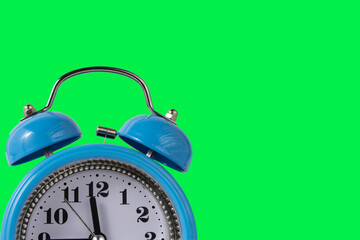 Blue alarm clock with copy space on a green background.