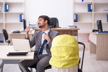 Young male employee looking after new born at workplace