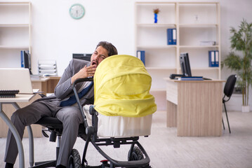 Young male employee looking after new born at workplace