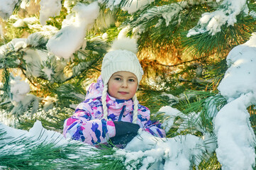 A little girl in a warm sports jacket on a winter walk in the woods