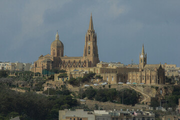 Fototapeta na wymiar View to town from water sailing towards coast with old buildings in Malta, Gozo