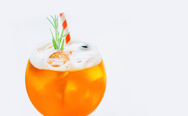 Close up glass of ice cold Aperol spritz cocktail decorated with rosemary and red striped straw served in a wine glass on white background.