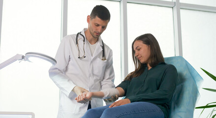 Fototapeta premium Planned Preventive Medical Examination of a Young Woman in the Clinic. The Doctor Measures the Blood Pressure of the Patient in the Office of the Clinic. Health Insurance Medical Service Concept.