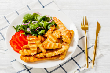 grilled chicken strips on a plate with vegetables