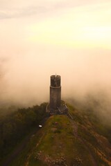 A view to the castle tower with morning fog and clouds around at Hazmburk, Czech republic