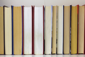 Books.Several books are in a row on a shelf or in a closet.