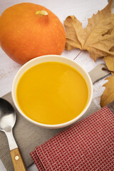 soupe au potiron avec feuilles d'automne et cuillère sur fond blanc