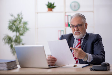 Old male employee working in the office