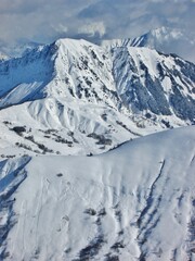 Beautiful Mountain View. French Alps in the Winter. Les Sybelles. Snowy mountains against cloudy sky. Vertical View.