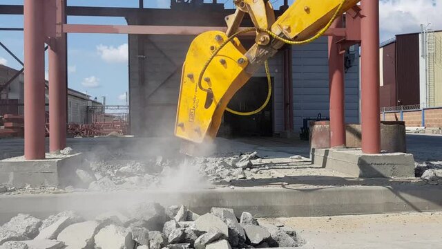 Professional demolition of reinforced concrete structures using industrial hydraulic hammer with excavator. Rods of metal fittings. Wreckage and crumbles of concrete.