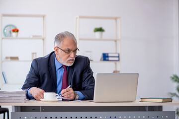 Old male employee working in the office